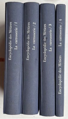 Quatre livres bleus sont alignés sur une table blanche
