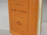 un livre orange posé sur une table, à côté d'une table blanche