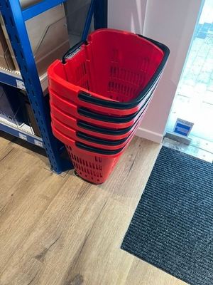 un panier rouge posé par terre à côté d'une étagère bleue
