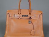 an orange leather handbag with a lock on the handle