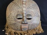an image of a wooden mask with fringes on a black background