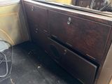 a brown cabinet and a fan in the corner of a room