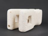 two pieces of white stone with holes in them on a black surface