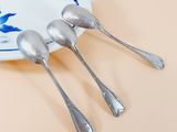 three silver spoons on a plate with a blue and white design