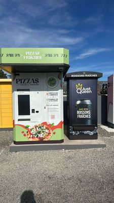 a vending machine in a parking lot next to a trash can