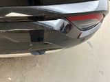 the rear end of a black car with a red tail light