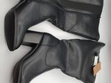 two pairs of black boots sitting on top of a white surface