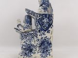 a blue and white figurine of a man reading a book