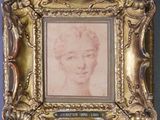 On y voit une vieille photo représentant le visage d'une femme, encadrée dans un cadre doré.