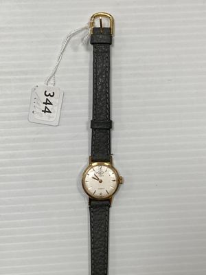 gros plan d'une montre sur une surface blanche avec une étiquette de prix