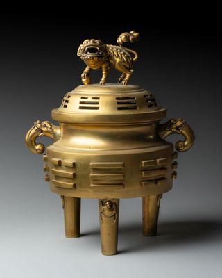 an image of a gold incense box with two lions on top
