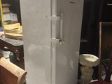 un réfrigérateur blanc posé dans une pièce, à côté d'un banc