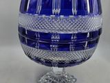 une photo représentant un œuf en verre bleu posé sur un socle, accompagné d'une carte