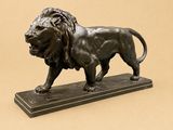 bronze statue of a lion on a marble base on a beige background