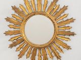 un motif doré en forme de rayons de soleil accroché au mur au-dessus d'un miroir