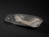 an old silver bowl on a black surface with a black background