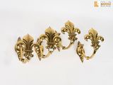 un lot de quatre crochets muraux en laiton en forme de fleur de lys