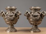 two silver vases sitting on top of a table next to each other
