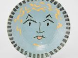 une assiette bleue et jaune sur laquelle est peint un visage