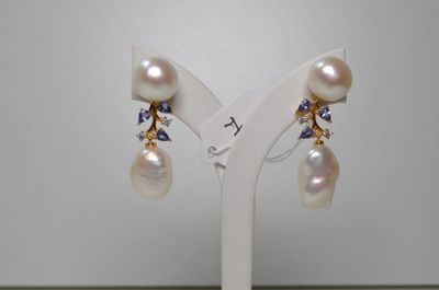 une paire de boucles d'oreilles en perles et saphirs exposée sur un présentoir blanc