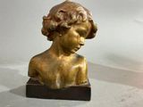 une statue en bronze représentant un jeune garçon, posée sur un socle en marbre