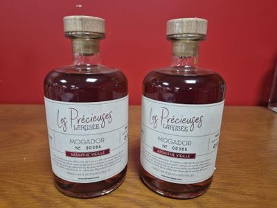 Deux bouteilles d'alcool sont posées sur une table devant un mur rouge.