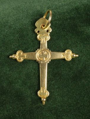 un gros plan d'une croix en or posée sur un tissu vert