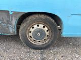a blue van with a flat tire on the side of the road