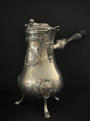 une cafetière en argent avec une anse, sur fond noir