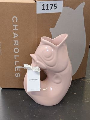 a pink cat shaped vase with a tag in front of a cardboard box