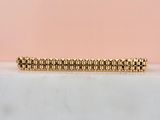 un gros plan d'un bracelet en or posé sur une surface en marbre