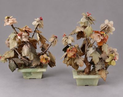 deux vases ornés de fleurs et de feuilles, posés sur un fond gris
