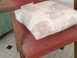 a red chair with a pillow on it in a room