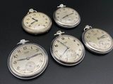 quatre montres de poche en argent posées les unes à côté des autres sur une table