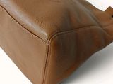 brown leather handbag on a white background with a blue label