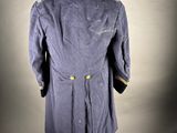 the back view of a blue military coat on a mannequin stand