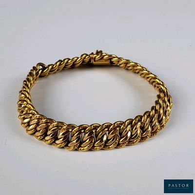 gros plan d'un bracelet en or sur une surface blanche