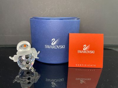 une petite figurine posée à côté d'une boîte de Swarovski