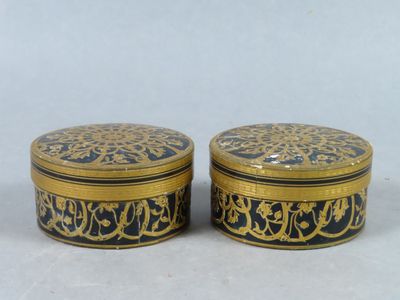 two black and gold boxes with designs on them on a white surface