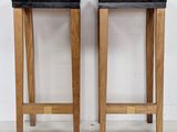 pair of wooden stools with black marble tops against a white wall