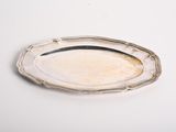 une assiette ancienne en argent sur un fond blanc, bordée d'argent