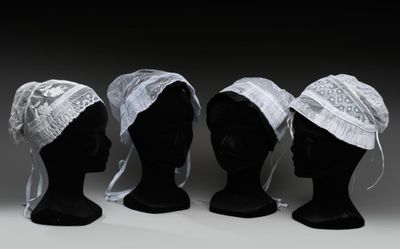 trois têtes de mannequins coiffées de chapeaux blancs sur fond noir
