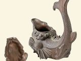a picture of a fish shaped teapot next to a shell
