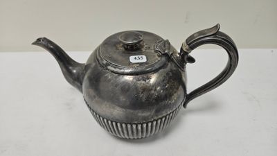 une vieille théière en argent avec une anse, posée sur une table blanche