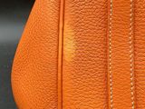 an orange purse with a zipper on the inside of it on a black surface