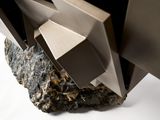 a close up of a metal object with a rock in front of it
