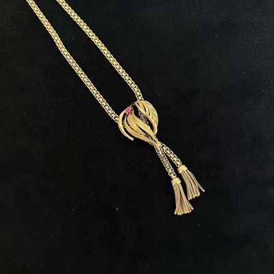 Gros plan sur un collier en or orné d'un oiseau