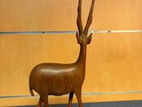 a wooden sculpture of a antelope standing on a pedestal