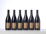six bottles of red wine lined up on a table