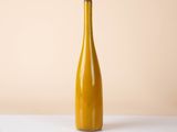 a yellow bottle of wine on a white table against a beige background